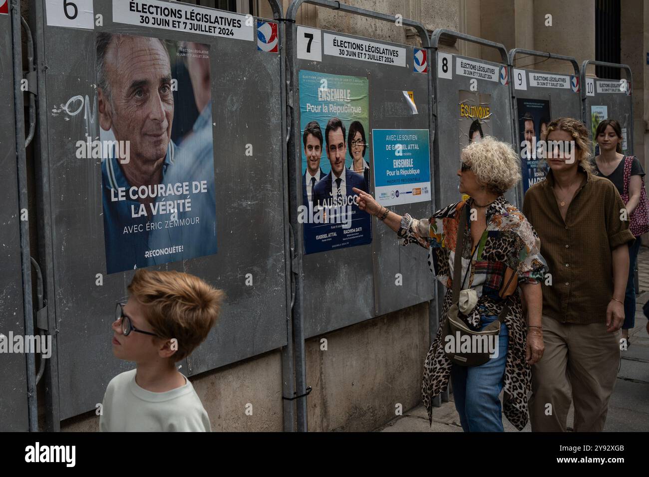 Les gens passent devant les affiches de campagne lors du premier tour des élections législatives anticipées en France, à Paris, le dimanche 30 juin, 2024. Siegfried M. Banque D'Images