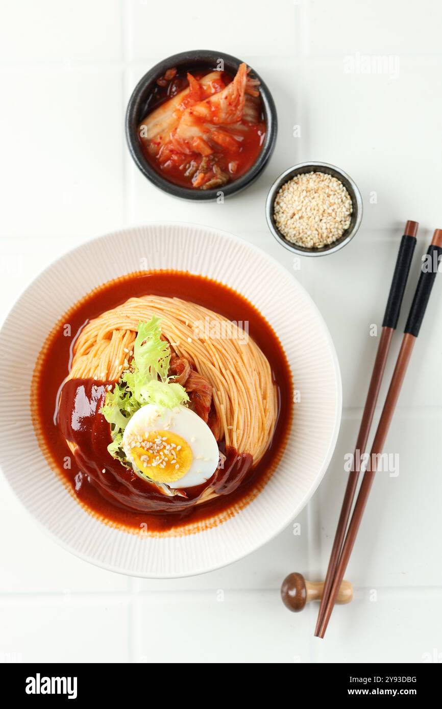 Vue de dessus coréen Kimchi Bibim Guksu, nouilles froides style coréen sur table blanche Banque D'Images