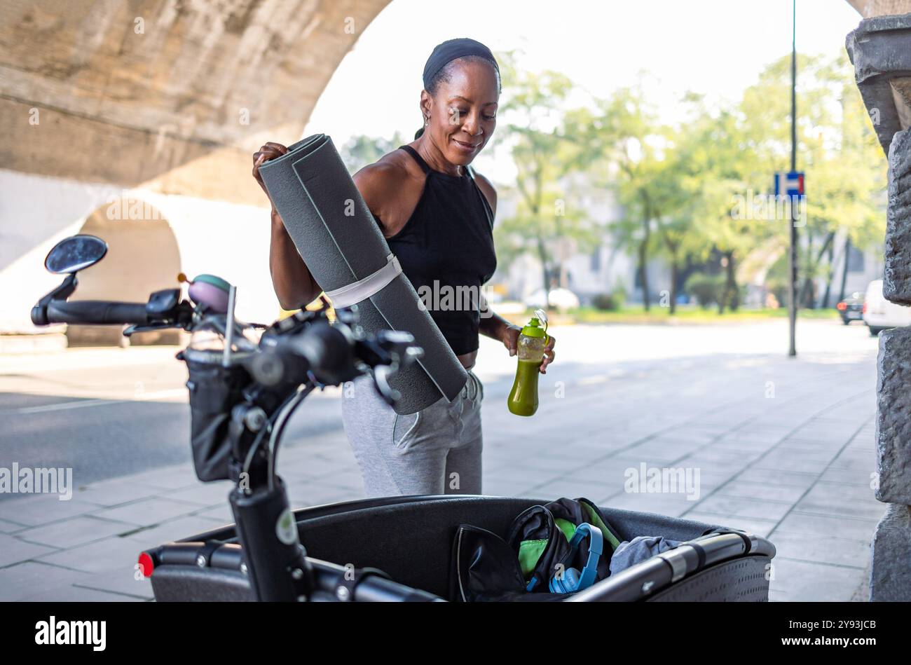 Femme qui va à la salle de gym emballe de l'équipement de sport dans un vélo cargo Banque D'Images