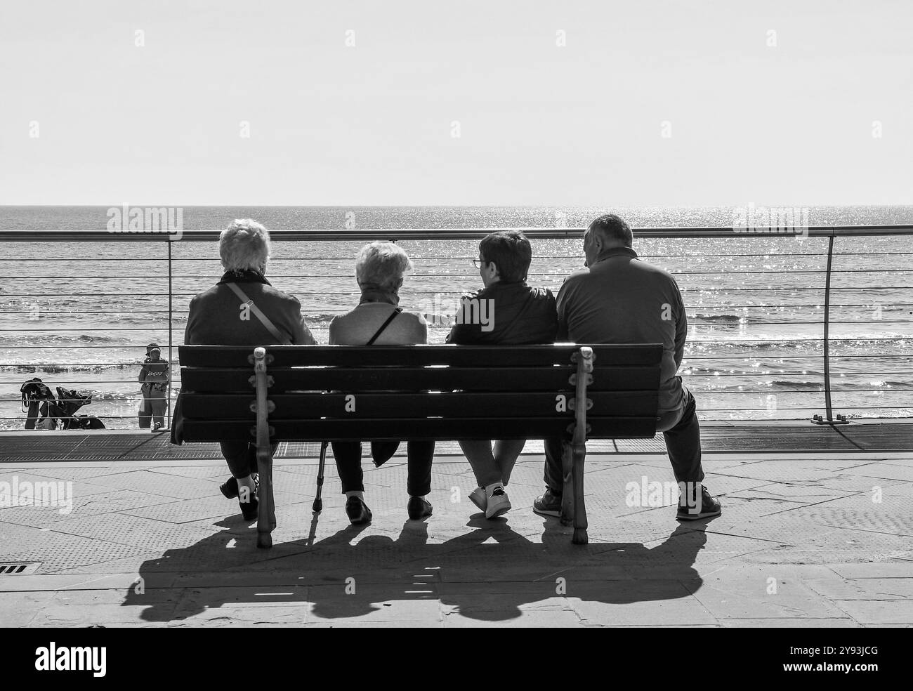 Photo noir et blanc. Trois dames âgées et un gentleman se reposant sur un banc sur la promenade de la station balnéaire, Alassio, Savona, Ligurie, Italie Banque D'Images