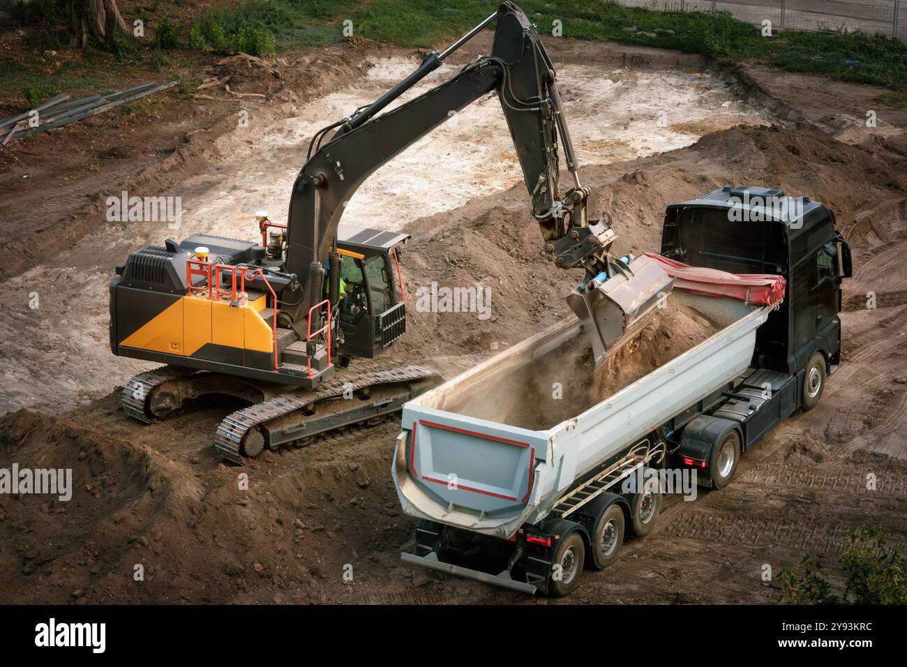 Excavatrice chargeant la terre dans un camion à benne basculante sur un chantier de construction, belle vue d'en haut Banque D'Images