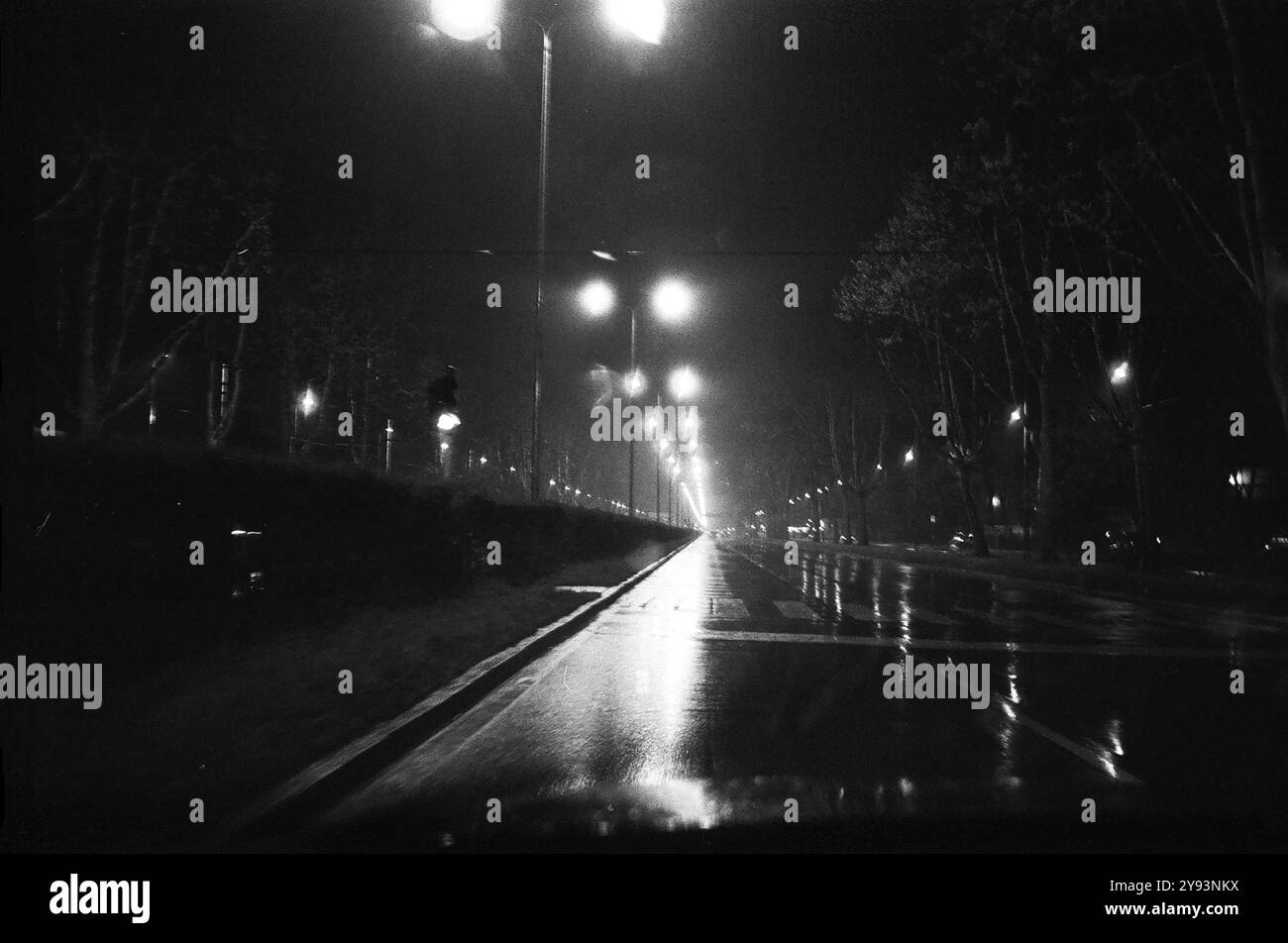 Dans la nuit humide de la route avec des lumières éblouissantes et des ombres floues à Milan Banque D'Images