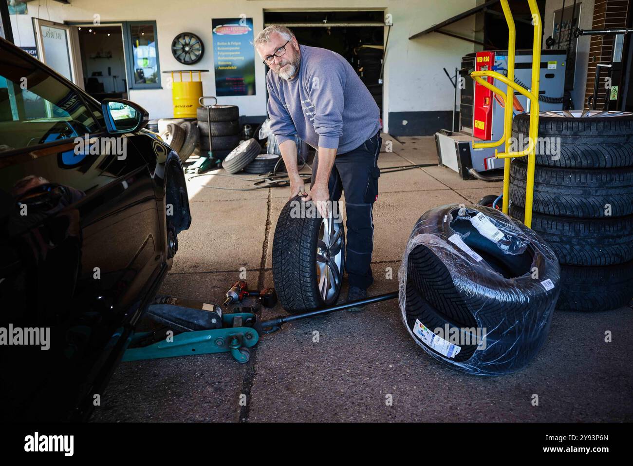 07.10.2024, Geretsberg, AUT, Unterwegs in Innviertel, Symbolbild, Themenbild, Verschiedene Themenbilder, Reifen Wechsel, im Bild Ein Mechaniker montiert Winterreifen an einem Auto in einer KFZ-Werkstatt. AM 1. Novembre débutant à Österreich für Pkw und LKW bis 3,5 Tonnen die situative Winterausrüstungspflicht. // Un mécanicien automobile monte des pneus hiver sur une voiture dans un garage. Le 1er novembre, l'obligation d'équipement hivernal de situation commence en Autriche pour les voitures particulières et les camions jusqu'à 3,5 tonnes, Autriche, Reifen, Montieren, montage, Wuchten, *** 07 10 2024, Geretsberg, AUT, Unterwegs in Innviertel, S Banque D'Images