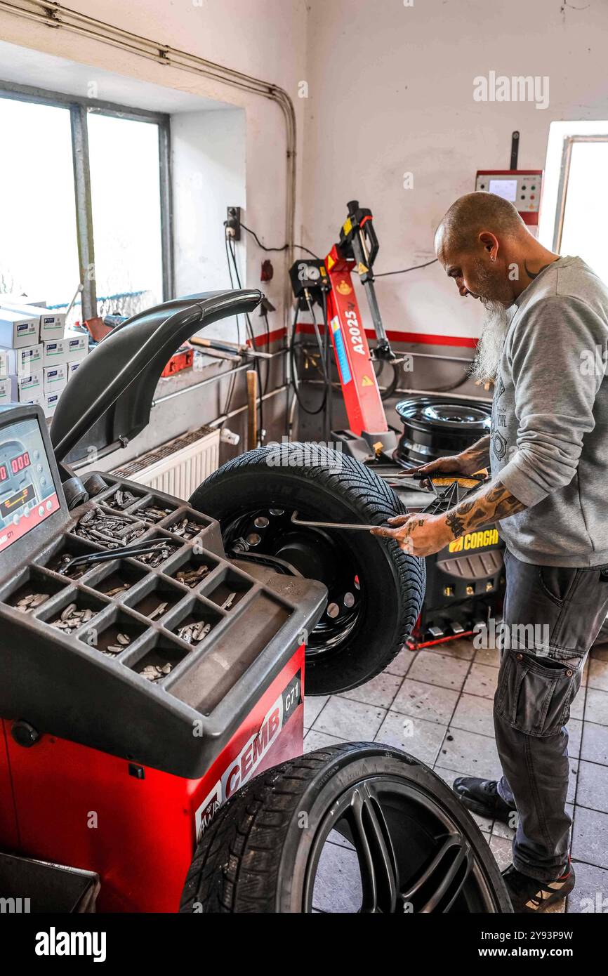 07.10.2024, Geretsberg, AUT, Unterwegs in Innviertel, Symbolbild, Themenbild, Verschiedene Themenbilder, Reifen Wechsel, im Bild Ein Mechaniker montiert Winterreifen an einem Auto in einer KFZ-Werkstatt. AM 1. Novembre débutant à Österreich für Pkw und LKW bis 3,5 Tonnen die situative Winterausrüstungspflicht. // Un mécanicien automobile monte des pneus hiver sur une voiture dans un garage. Le 1er novembre, l'obligation d'équipement hivernal de situation commence en Autriche pour les voitures particulières et les camions jusqu'à 3,5 tonnes, Autriche, Reifen, Montieren, montage, Wuchten, *** 07 10 2024, Geretsberg, AUT, Unterwegs in Innviertel, S Banque D'Images