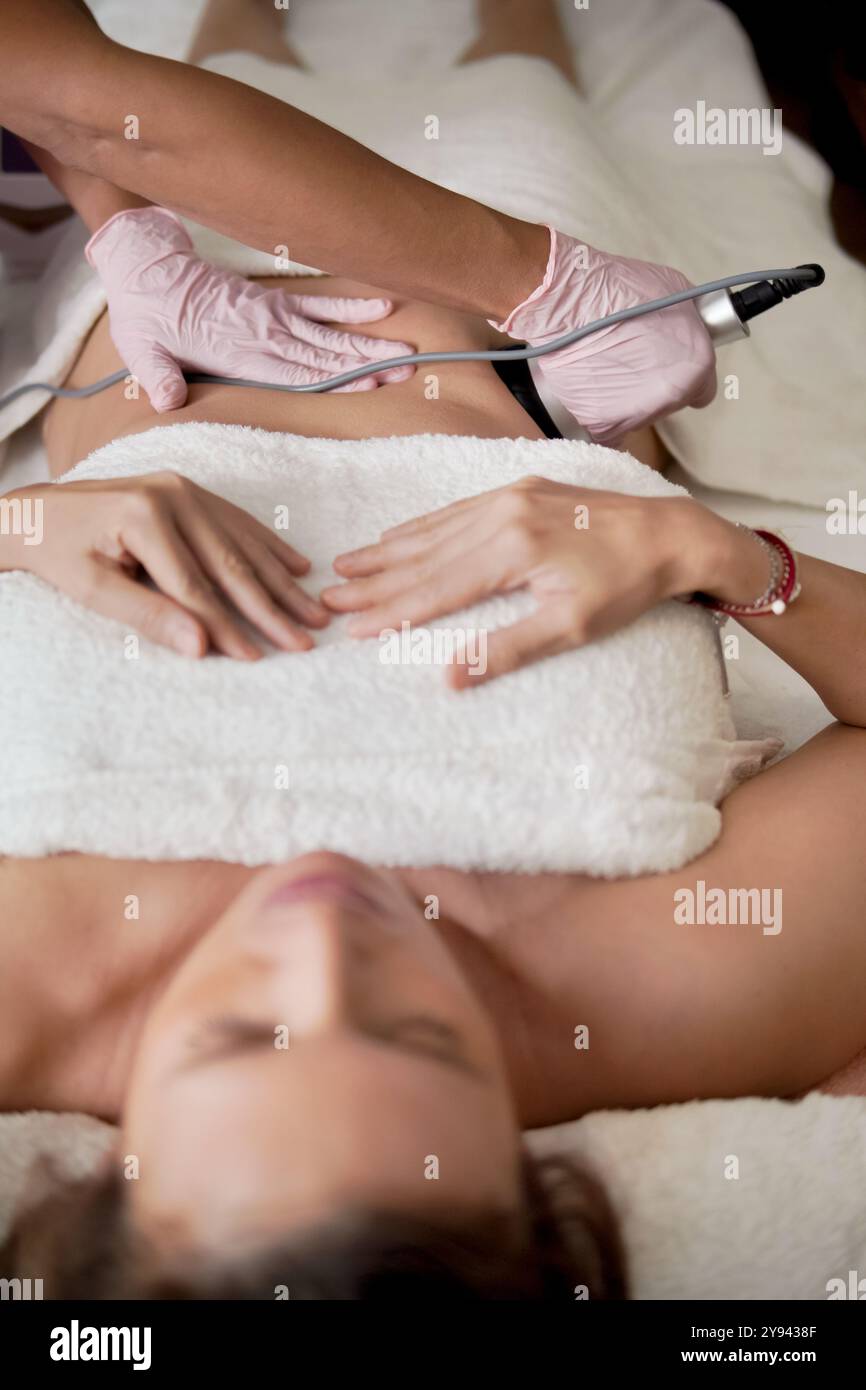 Gros plan d'une femme recevant un massage thérapeutique à la maison. Ses yeux sont fermés, appréciant la relaxation que la thérapeute féminine utilise un outil pour les tis profonds Banque D'Images