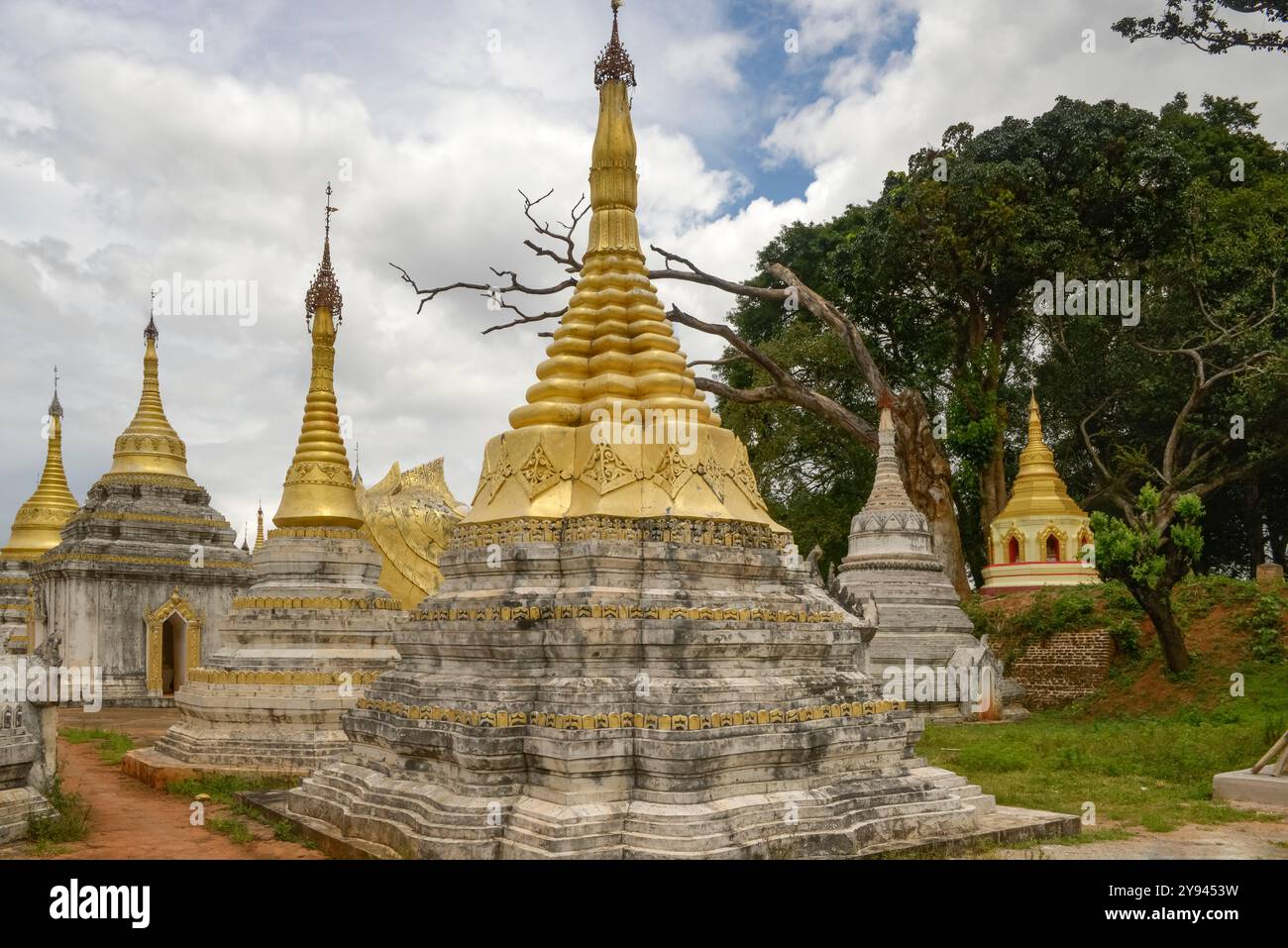 Stupas doré et blanc au milieu d'une végétation luxuriante à Pindaya, Myanmar, véhiculant un sentiment de paix et d'histoire. Banque D'Images