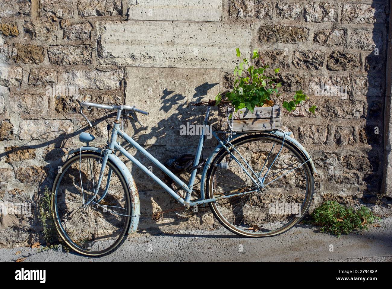 Un vieux vélo bleu pastel rouillé avec un pneu crevé, sans selle debout contre un mur de briques. copier l'espace Banque D'Images