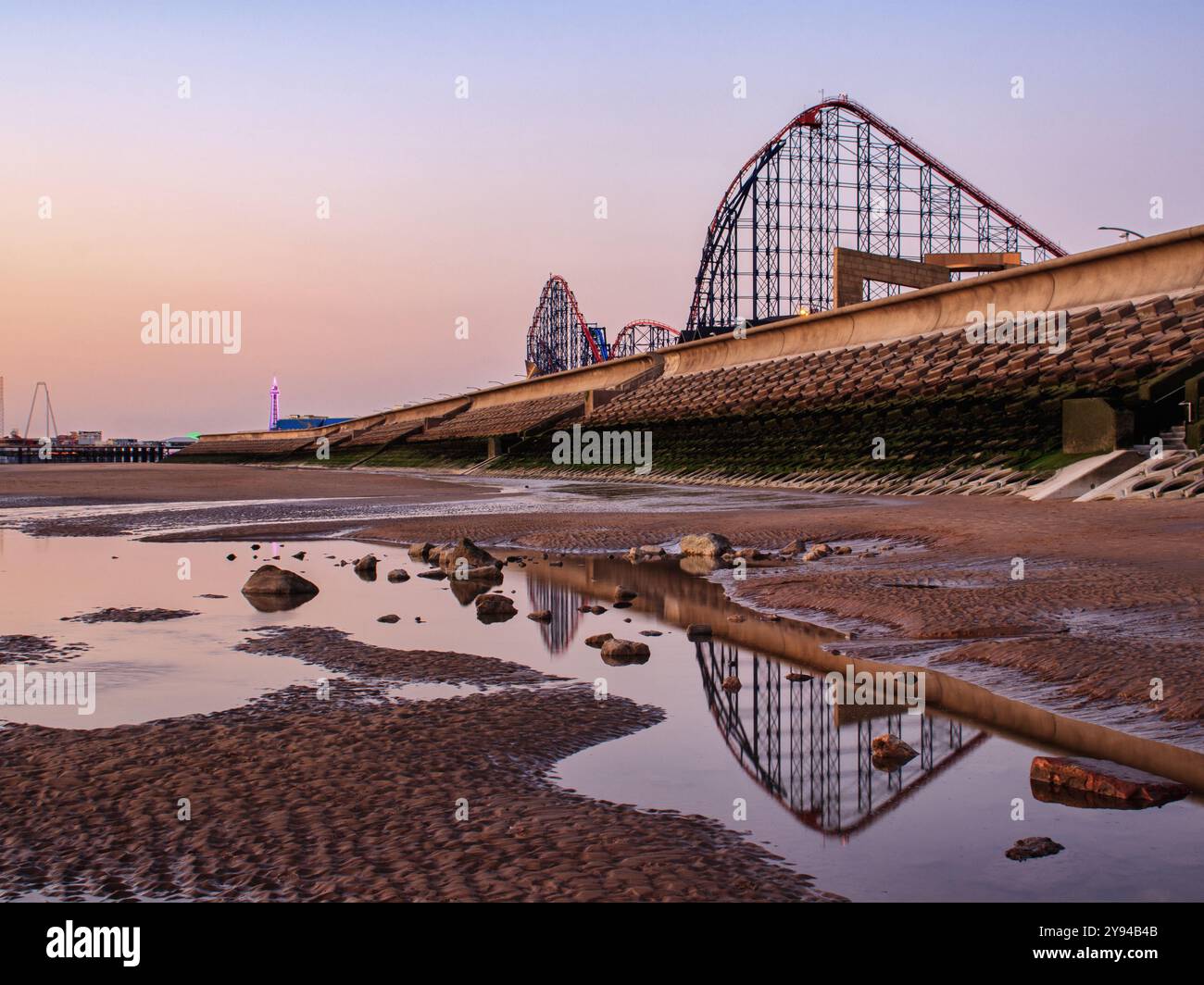 Reflets du grand sur une plage désolée de Blackpool à marée basse, avec la tour illuminée au loin Banque D'Images