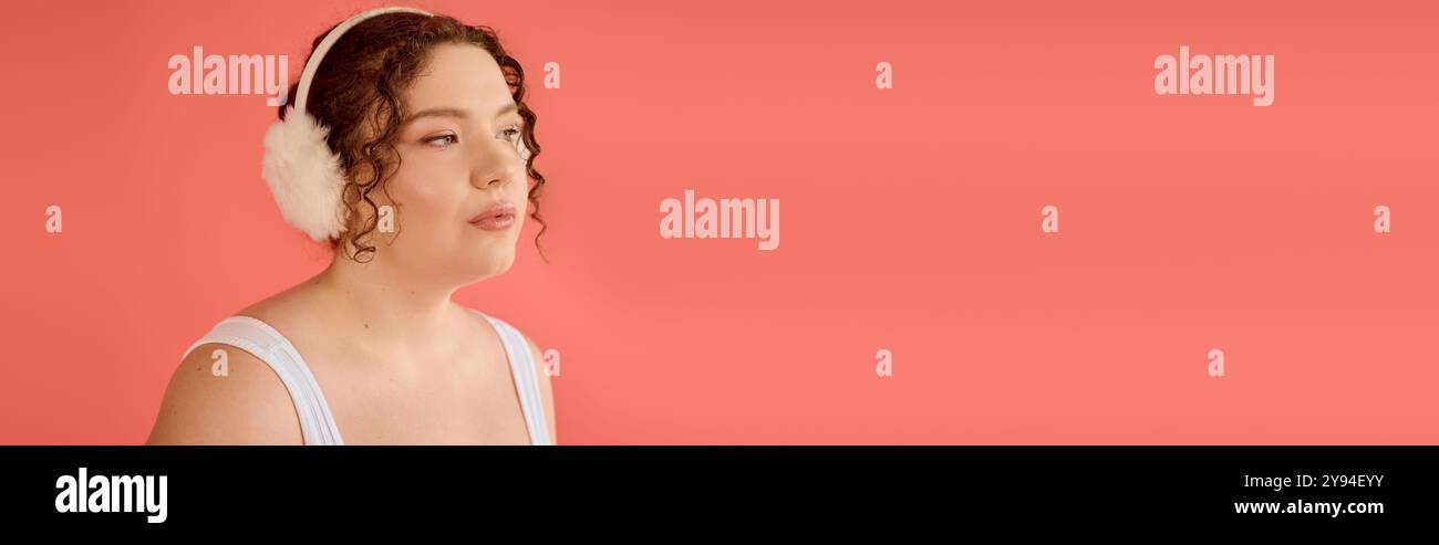 Une superbe femme de grande taille met en valeur sa beauté, portant des cache-oreilles doux et embrassant son style. Banque D'Images