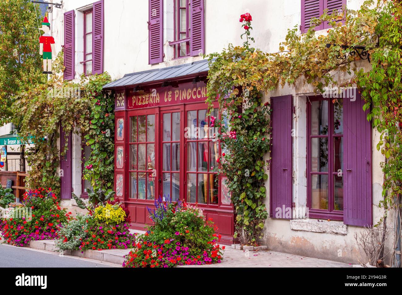 Fenêtres pourpres à volets, fleurs et façade rouge de pizzeria dans le village pittoresque de Cheverny, mieux connu pour son château, Cheverny, France Banque D'Images