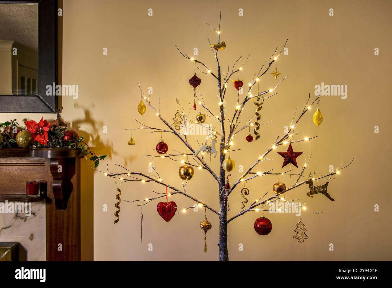 Sapin de Noël moderne de style brindille décoré dans des décorations de Noël traditionnelles rouges et dorées avec effet neige et ligthes sur Banque D'Images