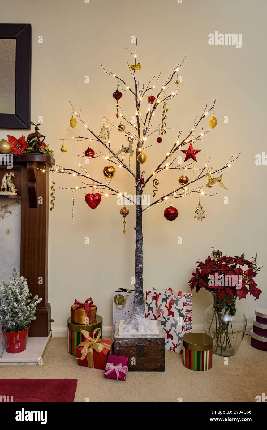 Sapin de Noël moderne de style brindille décoré dans des décorations de Noël traditionnelles rouges et dorées avec effet neige et ligthes sur Banque D'Images