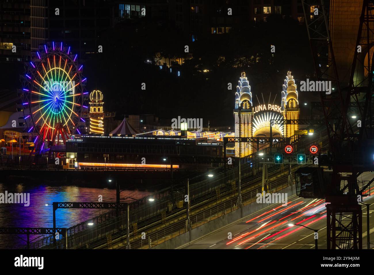 Sydney, Australie - 9 février 2023 : longue exposition de voitures traversant le pont du port de Sydney la nuit, avec la célèbre foire funfair Luna Park de l'autre côté de la baie. Banque D'Images