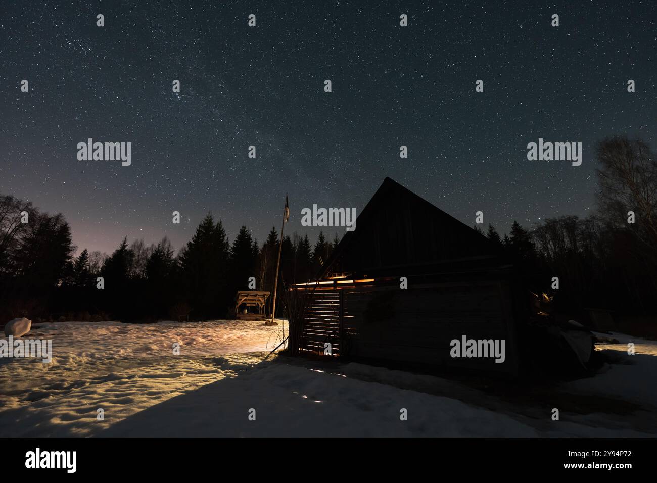 Scène nocturne en hiver, ferme estonienne Kollassaare isolée dans la forêt, beau ciel étoilé. Banque D'Images