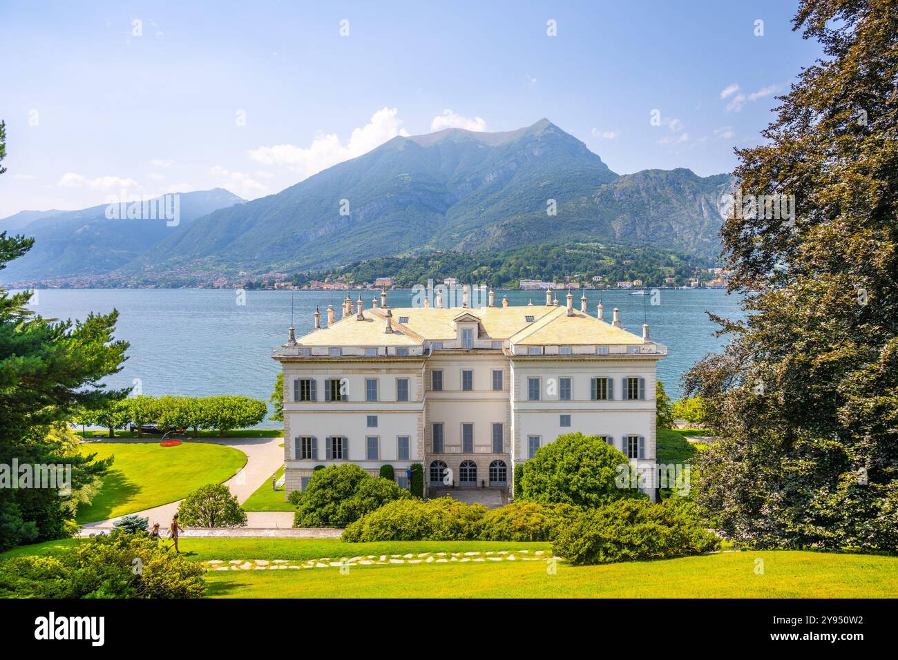 La Villa Melzi, de style néoclassique, surplombe les eaux sereines du lac de Côme à Bellagio. Des montagnes majestueuses s'élèvent en arrière-plan, mettant en valeur l'architecture et les jardins époustouflants de la villa. Banque D'Images