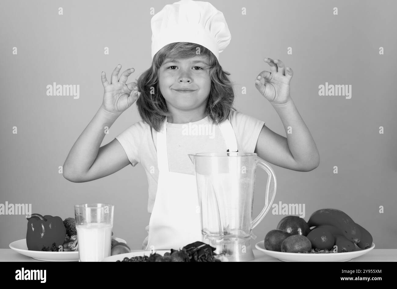 Tablier de cuisinier et chapeau de chef habillés pour enfants isolés sur fond de studio. Alimentation saine alimentation pour enfants. Banque D'Images