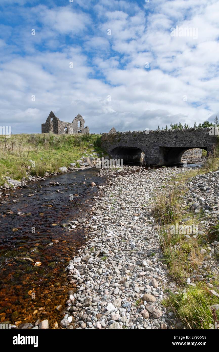 Cette photographie capture les vestiges en ruines du Cooper's Lodge avec un pont de pierre au premier plan, enjambant un ruisseau doux. La verdure luxuriante a Banque D'Images