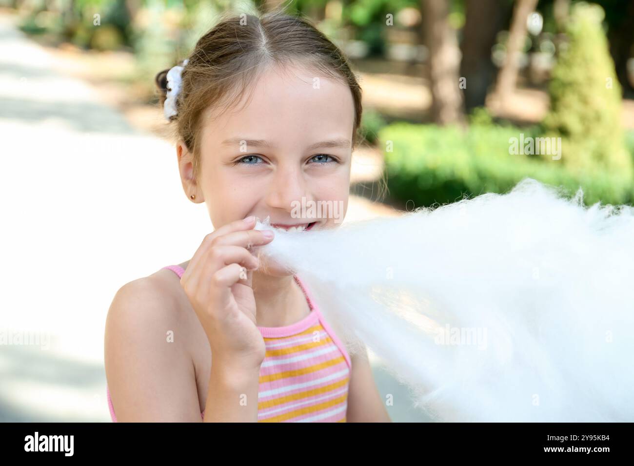 Portrait de petite fille mangeant de la barbe à papa sucrée dans le parc Banque D'Images