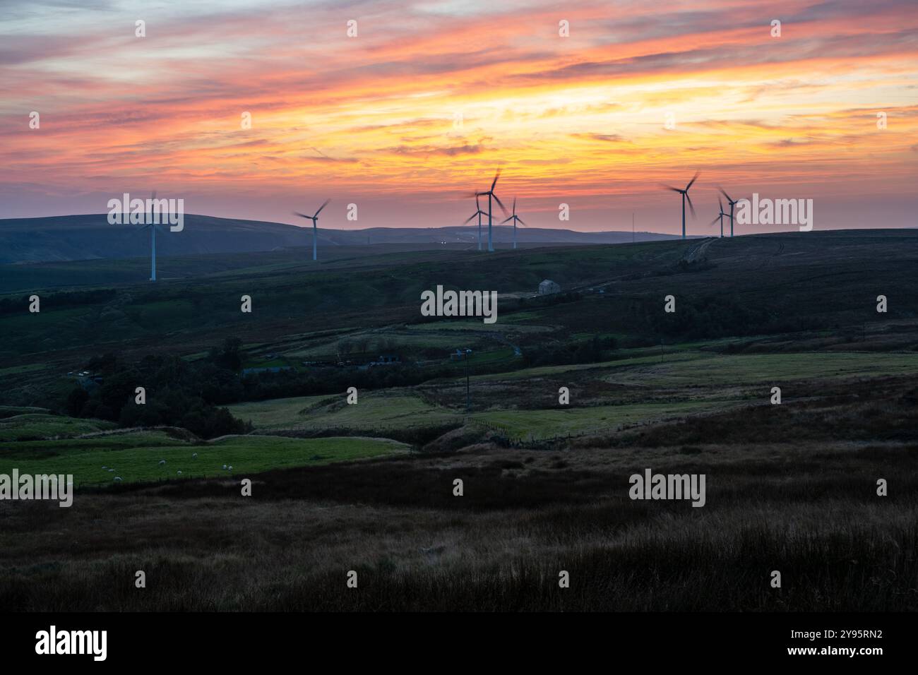 Le soleil se couche derrière la ferme éolienne de Coal Clough sur Warcock Hill au-dessus de Burnley dans le Lancashire. Banque D'Images