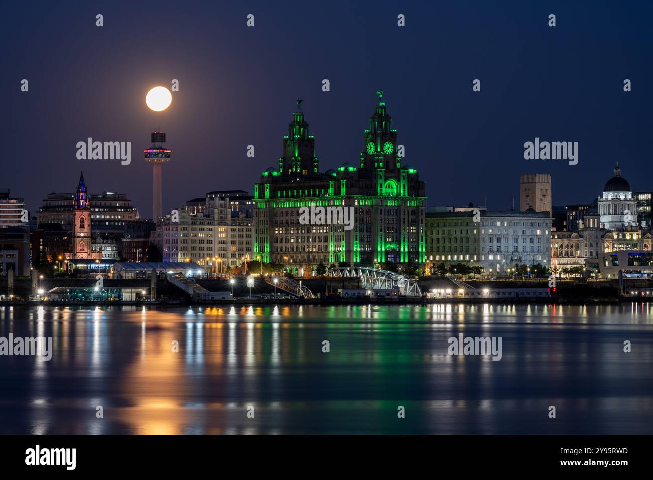 Une pleine lune se lève au-dessus de la rivière Mersey et de l'horizon de Liverpool, y compris le monument Royal Liver Building. Banque D'Images