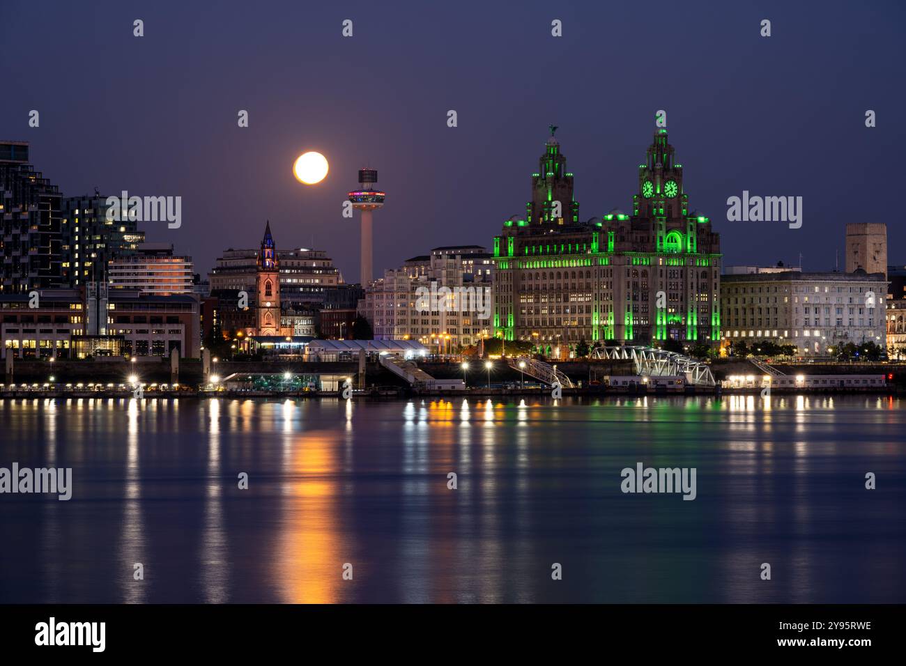 Une pleine lune se lève au-dessus de la rivière Mersey et de l'horizon de Liverpool, y compris le monument Royal Liver Building. Banque D'Images