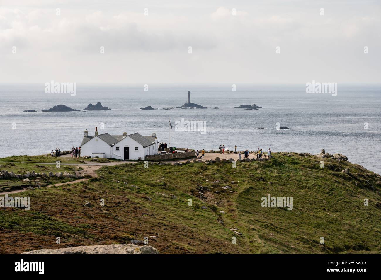 Les touristes visitent la première et la dernière maison à Dr Syntax's Head sur Cornwall's Land's End, avec des rochers de longships au loin. Banque D'Images
