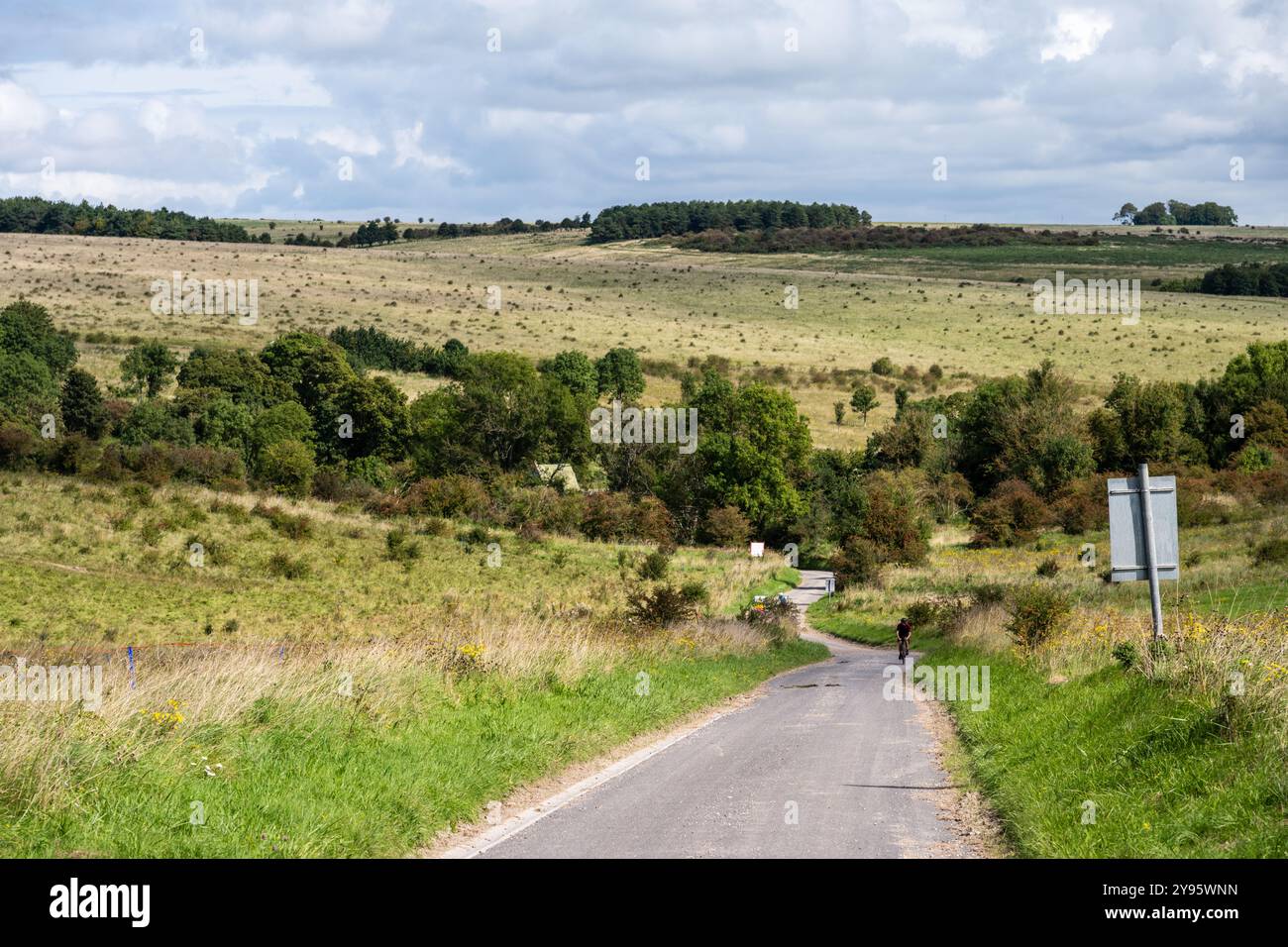 Un cycliste grimpe une colline sur une voie de campagne à travers Imber Range, une zone d'entraînement de l'armée britannique sur la plaine de Salisbury dans le Wiltshire. Banque D'Images