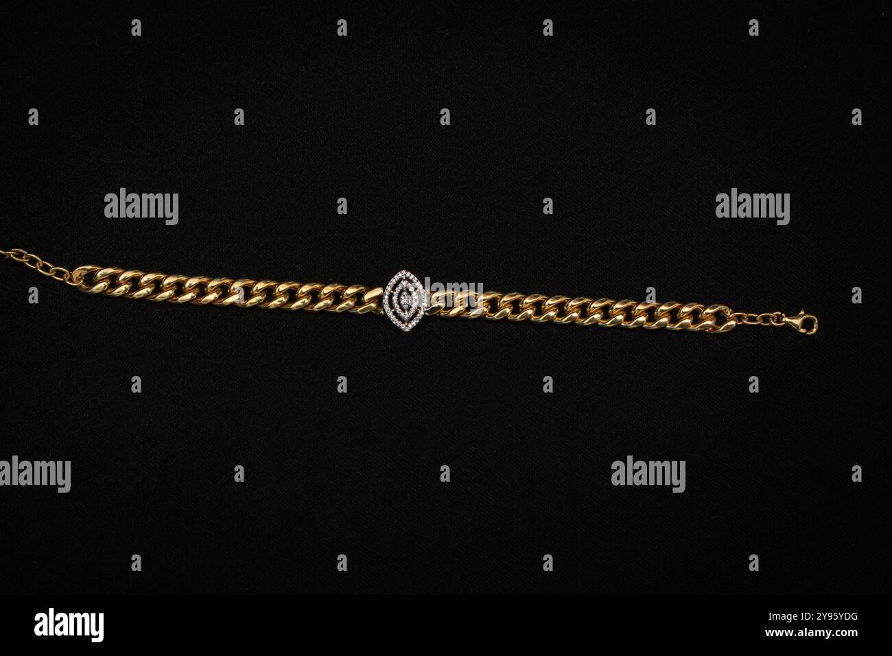 Un bracelet chaîne en or classique avec un beau pendentif oeil cloutée de diamant au centre. Cette pièce luxueuse ajoute une touche d'élégance et de protection Banque D'Images