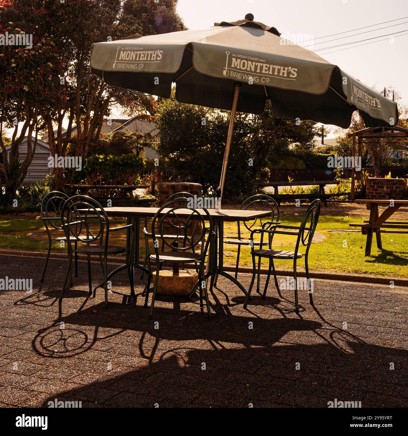 Karamea, côte ouest, île sud, Aotearoa / Nouvelle-Zélande - 21 septembre 2024 : salon de jardin de l'hôtel Karamea avec parasol de la brasserie Monteith / Banque D'Images
