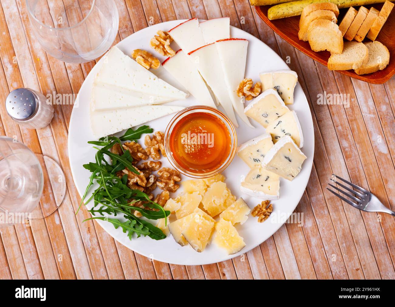 Différents types de fromage tranchés et servis sur une assiette avec un bol de miel, des noix Banque D'Images
