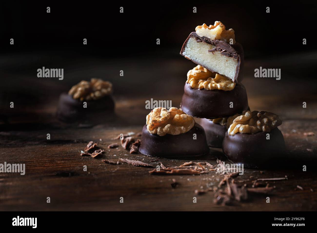 Pralines de massepain avec enrobage de chocolat noir et garniture de noix, entières et coupées en deux, empilées sur des planches rustiques de bois foncé, bonbons de vacances, spa de copie Banque D'Images