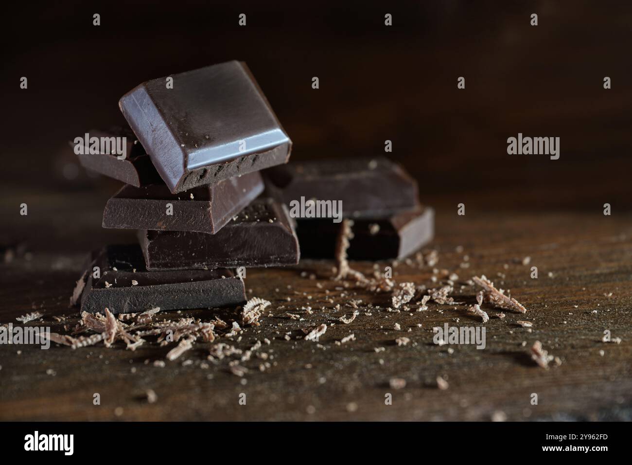 Morceaux de chocolat noir bio avec une teneur élevée en cacao et peu de sucre empilés sur des planches de bois rustique brun, une friandise sucrée légèrement saine avec Banque D'Images
