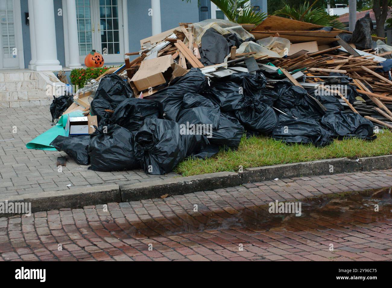 Gros tas de déchets, meubles, articles ménagers empilés sur le côté d'une bordure de rue en briques. Après une tempête endommageant l'inondation d'une onde de tempête d'eau. Attendez Banque D'Images