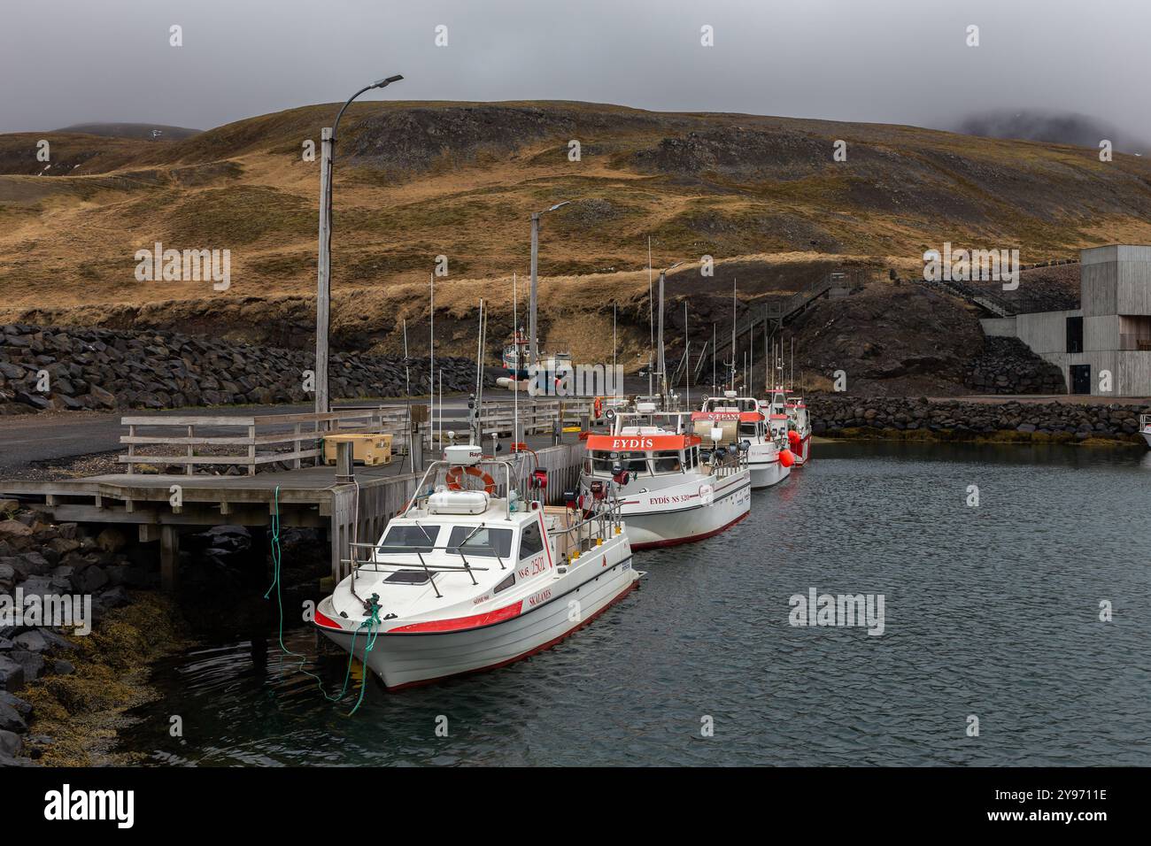 Hafnarholmi, Islande, 19.05.2022. Port de plaisance de Hafnarholmi à Borgarfjordur eystri avec des bateaux de pêche amarrés à la jetée en bois, montagnes nuageuses. Banque D'Images