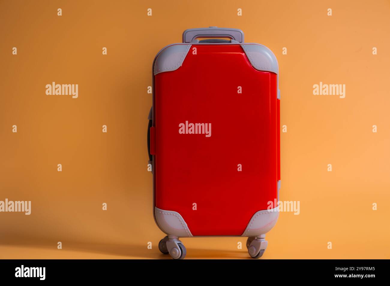 Valise miniature rouge isolée sur fond de corail orange voyage et concept de tourisme Banque D'Images