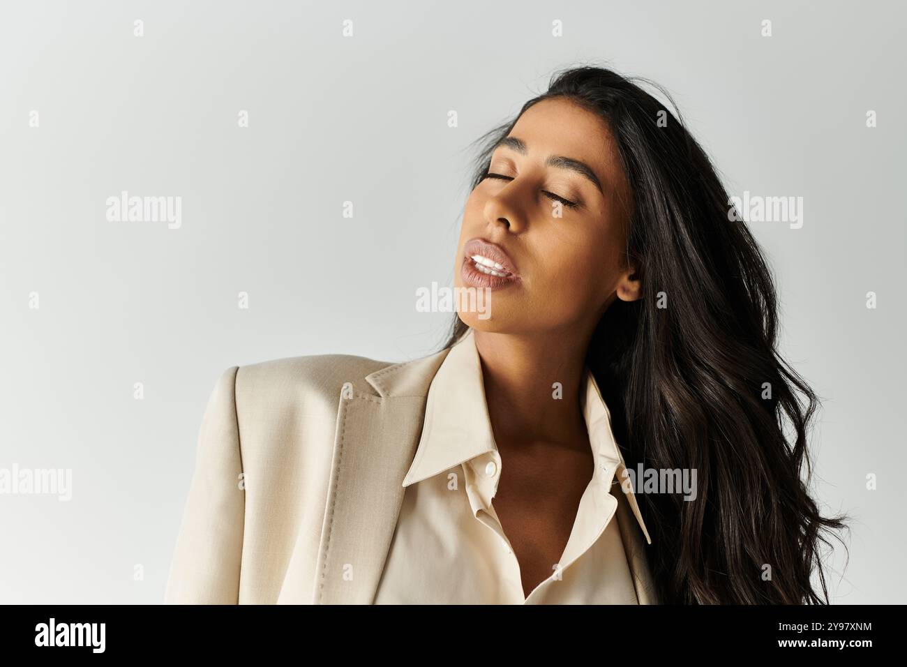 Une jeune femme vêtue d'une tenue chic respire la confiance et la grâce tout en frappant une pose. Banque D'Images