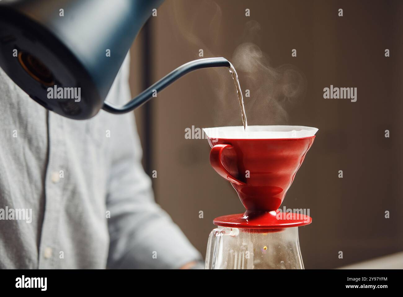 Barista versant de l'eau chaude dans le café rouge du café moderne Banque D'Images