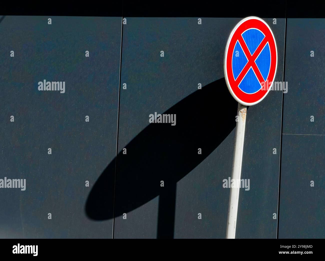 Pas d'arrêt : panneau de signalisation circulaire avec bleu et rouge contre un mur gris Banque D'Images