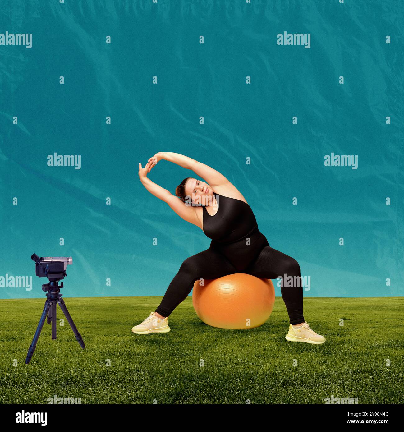 Femme courbée assise sur un grand ballon d'exercice et s'étirant sur fond bleu et herbe verte. Séance d'entraînement avec enregistrement de caméra. Art créatif Banque D'Images