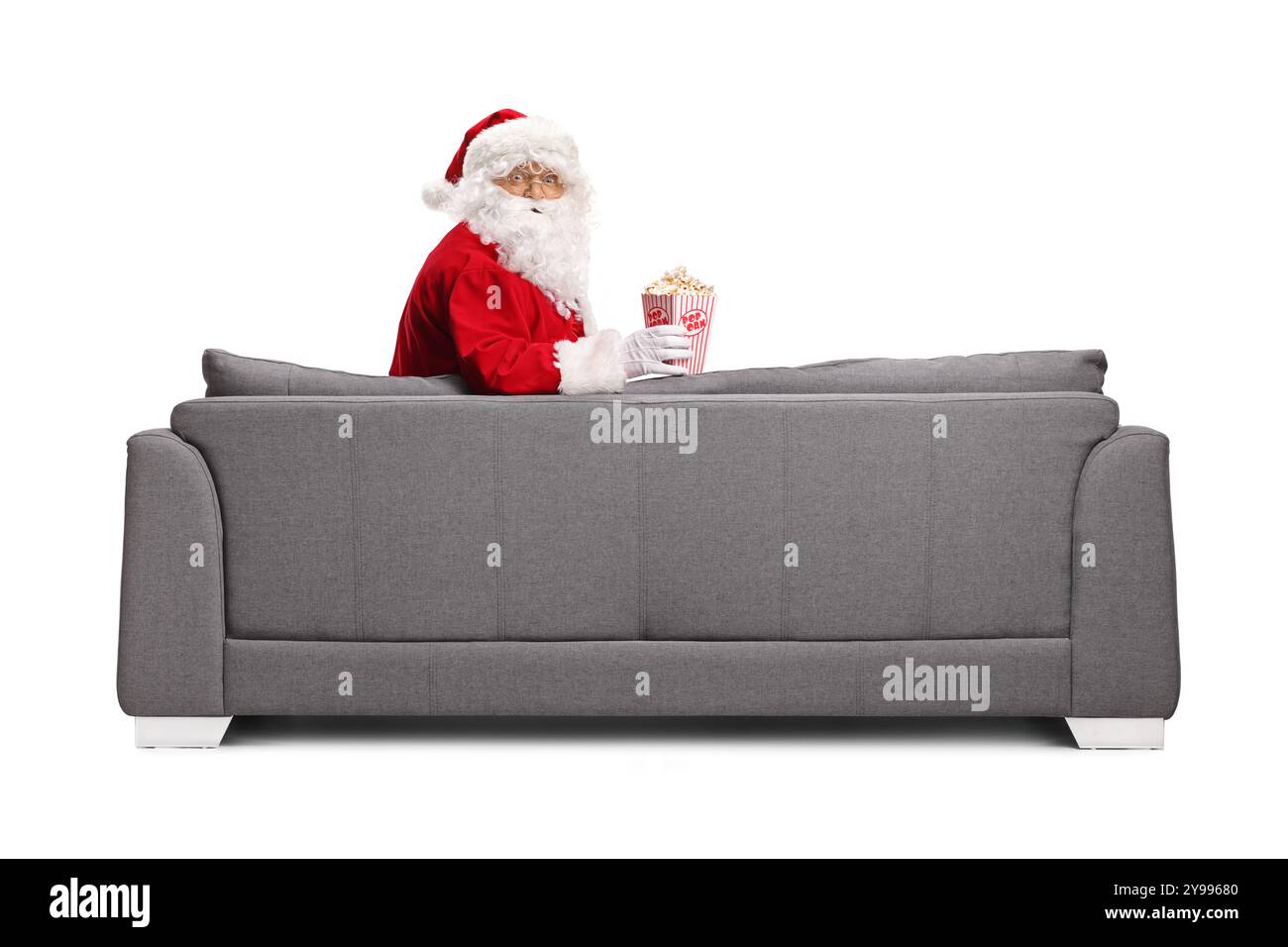 Père noël assis sur un canapé avec une boîte de pop-corn isolé sur fond blanc Banque D'Images