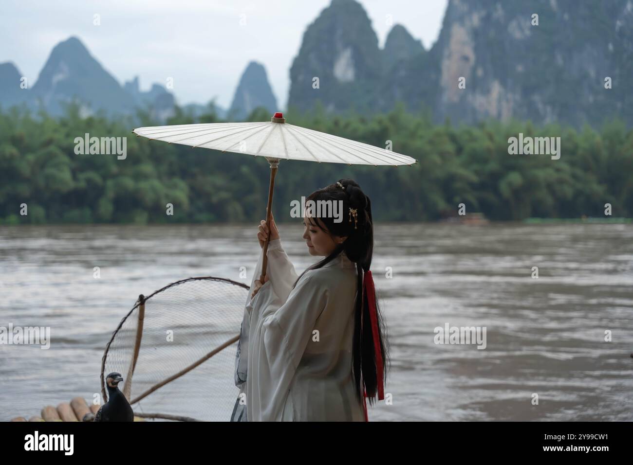 La fille modèle Hanfu tient le parapluie Deng le faisant tourner légèrement comme l'oiseau rabat des ailes. Séance photo en Chine Banque D'Images