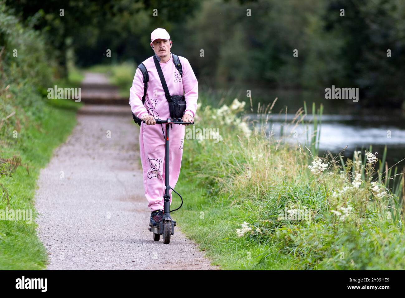 Un homme conduit un scooter électrique le long du chemin du canal au Grand Western canal, Tiverton, Devon, Royaume-Uni. Banque D'Images
