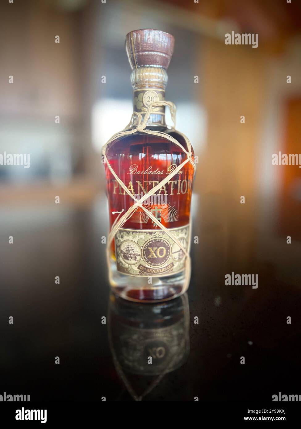 Une bouteille de rhum Plantation XO 20th Anniversary Barbados élégamment exposée, reflétant la lumière sur une surface noire Banque D'Images