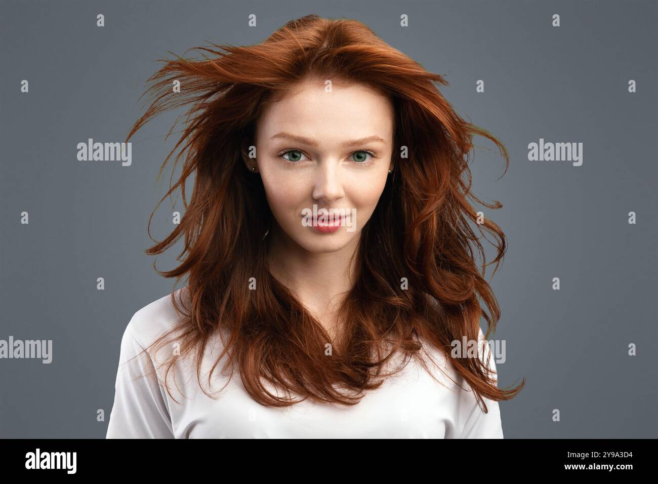 Jeune femme aux cheveux rouges posant sur fond blanc Banque D'Images