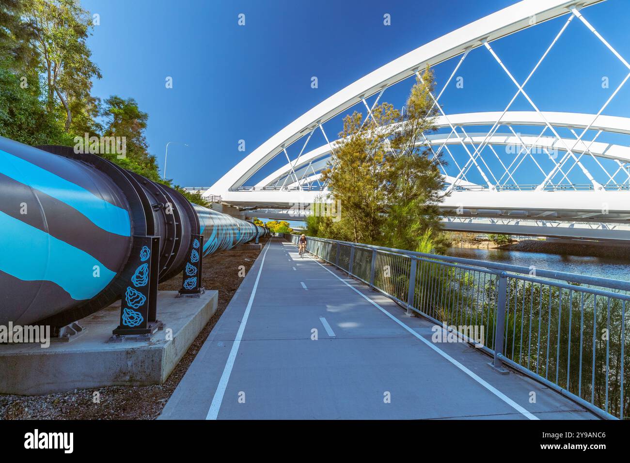 Sydney, Australie, 10 octobre 2024. Un pipeline de 800 mètres recouvert de graffitis a été renouvelé en une œuvre d’art inspirée des Premières Nations. Le pipeline longe Airport Drive et Alexandra canal à l'aéroport de Sydney pour transporter l'eau de l'usine de dessalement de Sydney vers d'autres parties de la ville. Il a été conçu par Dennis Golding et Carmen Glynn-Braun de Re-Right. JO Breneger et Leia Sidery ont peint le pipeline. Sa conception est basée sur les paysages des régions de Bidjigal, Gadigal et Dharawal. Sur la photo : la murale vue depuis le pont Ouest. Crédit : Robert Wallace / Wallace Media Network / Alamy Live News Banque D'Images