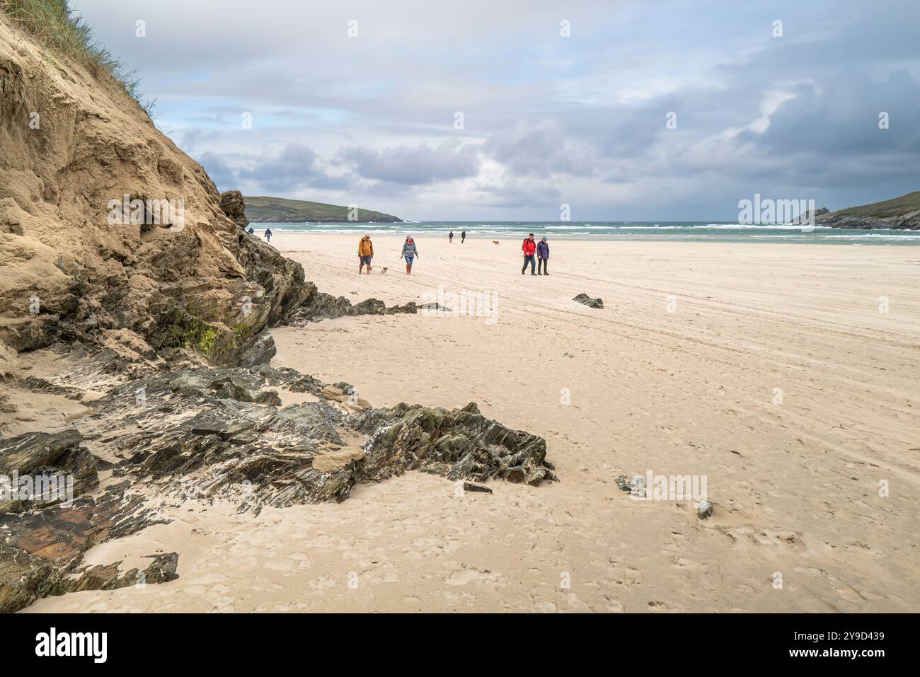 Les gens marchent devant le système instable de dunes de sable sur la plage de Crantock à Newquay en Cornouailles au Royaume-Uni. Banque D'Images