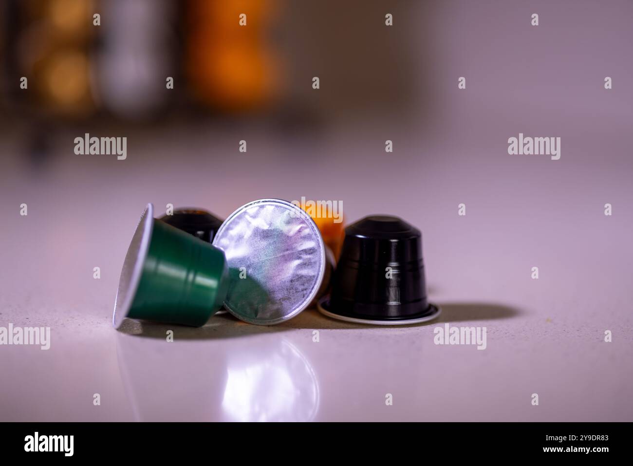 Diverses capsules de café sont placées à l'avant, tandis qu'un organisateur de capsules de café moderne peut être vu en arrière-plan, prêt pour l'infusion quotidienne du café Banque D'Images