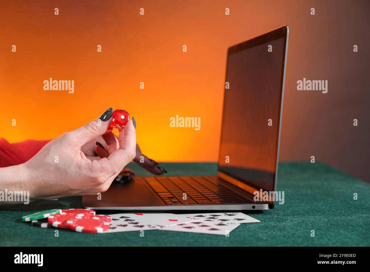 Poker en ligne. Femme tenant des dés et utilisant un ordinateur portable à la table verte, gros plan Banque D'Images