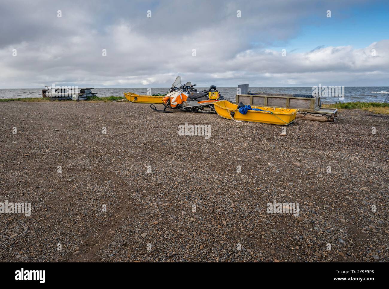 Traîneaux et motoneiges sur la rive de gravier de l'océan Arctique à Tuktoyaktuk, Territoires du Nord-Ouest, Canada Banque D'Images