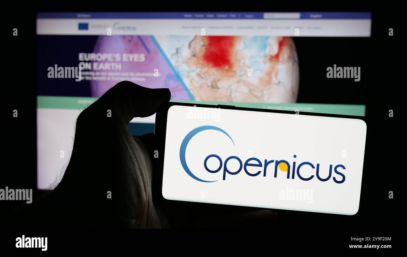 Personne tenant un smartphone avec le logo du projet d'observation de la Terre de l'ESA Copernicus sur l'écran en face du site Web. Concentrez-vous sur l'affichage du téléphone. Banque D'Images